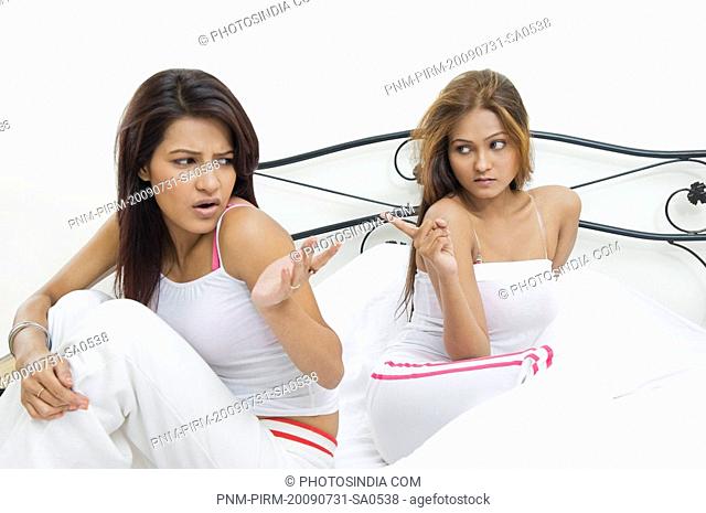 Lesbian couple sitting on the bed and looking sad