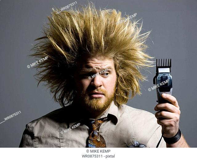 man with crazy hair holding hair clippers