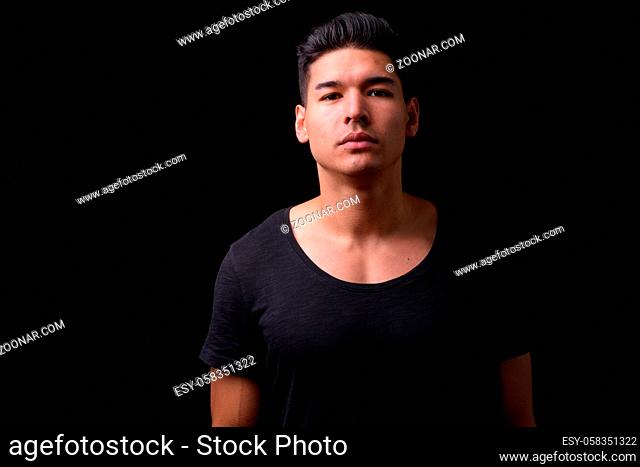 Studio shot of young handsome multi ethnic man against black background