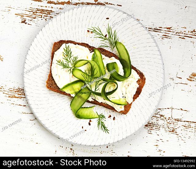 Bread topped with cream cheese, cucumber, and dill