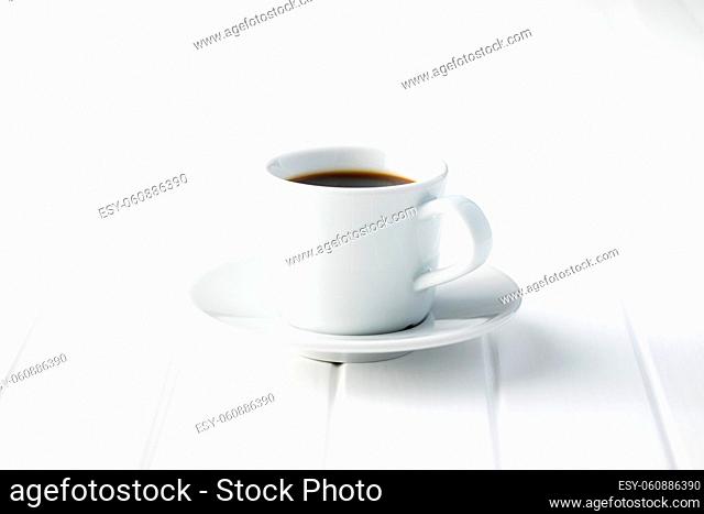 Black coffee in white mug on white wooden table
