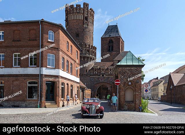 05 June 2021, Saxony-Anhalt, Tangermünde: A vintage car passes Tangermünde's best-preserved city gate, the Neustädter Tor