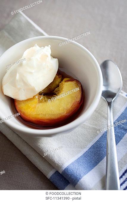 A honey-roasted peach with crème fraîche in a small white bowl