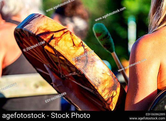 A colorful leather drum in Native American style is seen close up and from the side during an outdoor gig celebrating traditional music