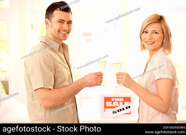 Happy couple celebrating new house purchase with champagne