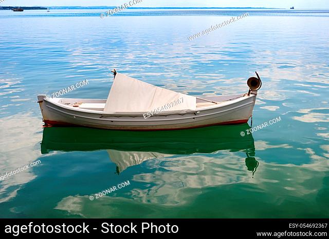 Very small white fishing boat at sea surface