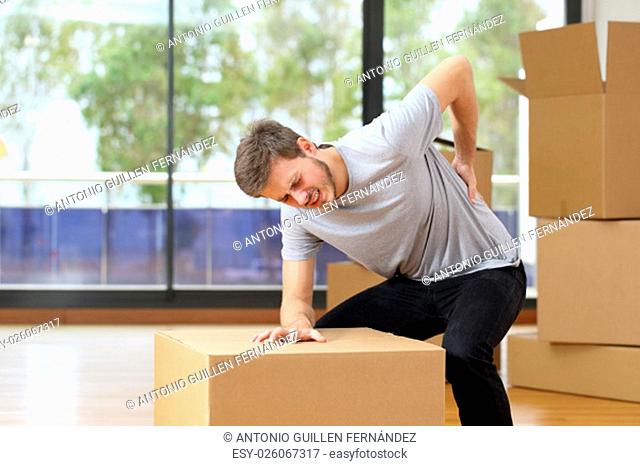 Man suffering back ache moving boxes in his new house