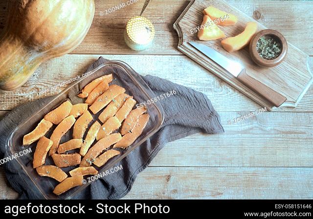 On a wooden table on a napkin pan with slices of pumpkin, baked with honey and herbs