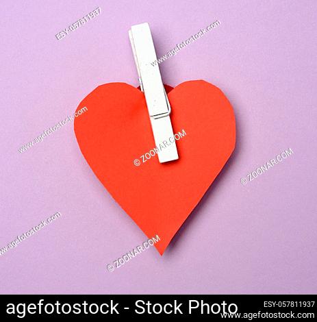 red paper heart pinned on a wooden clothespin, purple background