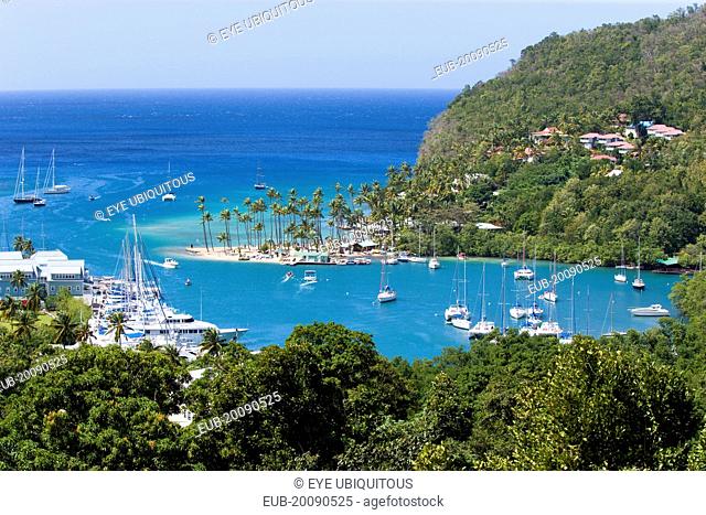 Marigot Bay The harbour with yachts at anchor the and lush surrounding valley. The small coconut palm tree lined beach of the Marigot Beach Club sits at the...