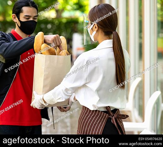 Deliverly asian bike man pick up bakery grocery bag from bakery shop to deliver to customer who make online order. Food deliverly service concept in new normal...