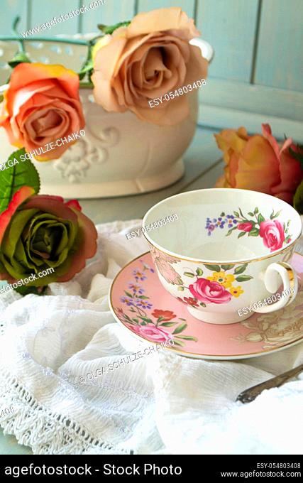 Antique floral cup, saucer and vintage roses, vertical