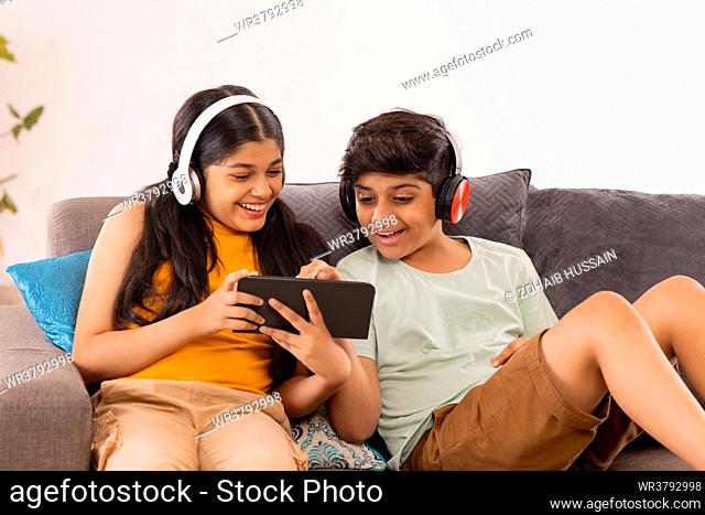 Boy and girl using digital tablet and listening music on headphones
