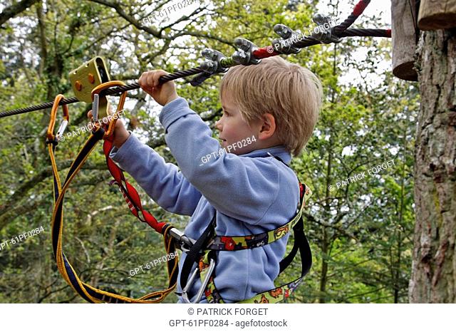 A BOY ATTACHING HIS CARABINERS TO A TYROLEAN TRAVERSE, AERIAL FOREST PARK ACROBRANCHE ON THE ROCHE D'OETRE, SAINT-PHILBERT SUR ORNE, SWISS NORMANDY, ORNE 61