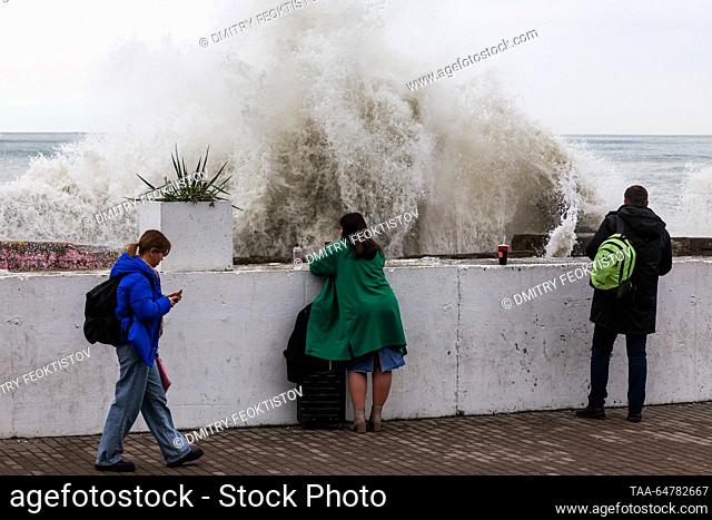 RUSSIA, SOCHI - NOVEMBER 13, 2023: People watch as waves smash against the coast during a storm on the Black Sea, in the Adler neighbourhood