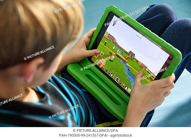 ILLUSTRATION - 02 March 2019, Hamburg: Mingus (9) plays the open world computer game Minecraft on his Ipad. According to projections, around 465