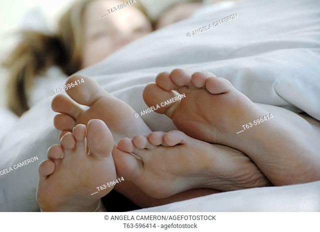 Young couples laying together in bed with feet in foreground