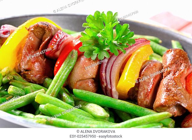 Liver skewer with green beans in a frying pan