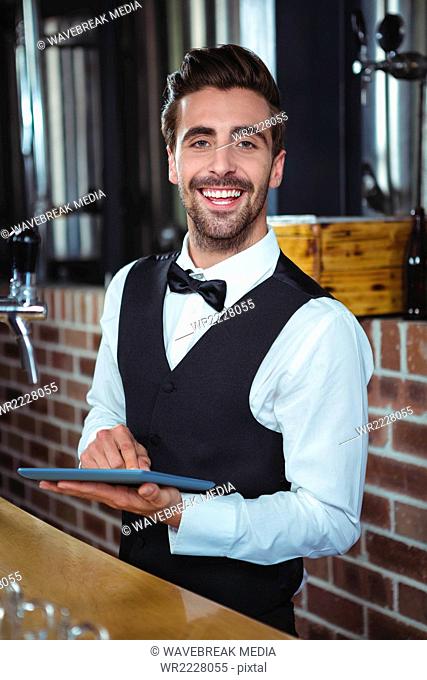 Handsome barman using tablet computer