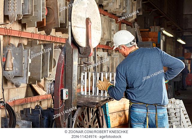 Mann als Arbeiter in einer Gießerei oder Metallfabrik sucht nach einer Gießform