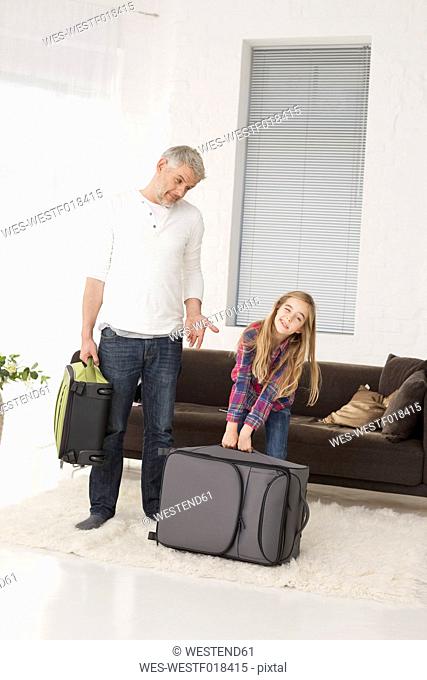 Germany, Leipzig, Father and daughter with packed luggage in apartment