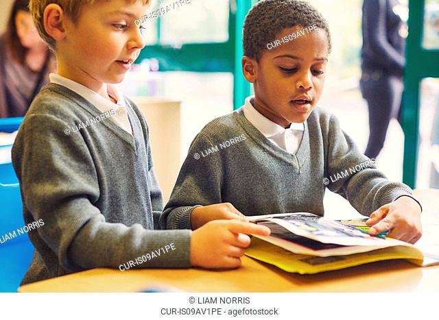 Two boys doing reading storybook at desk in elementary school classroom