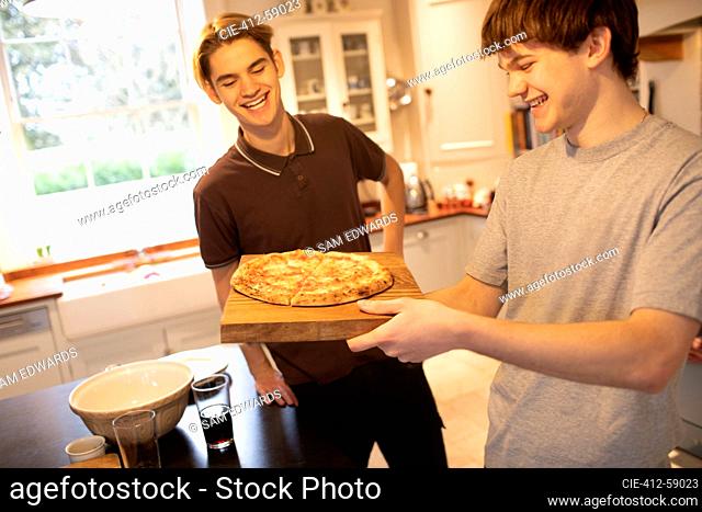 Happy teenage boys with pizza in kitchen