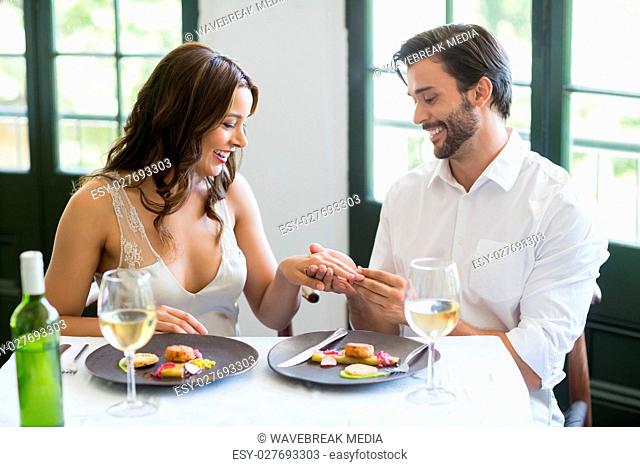 Man putting a ring on womans finger