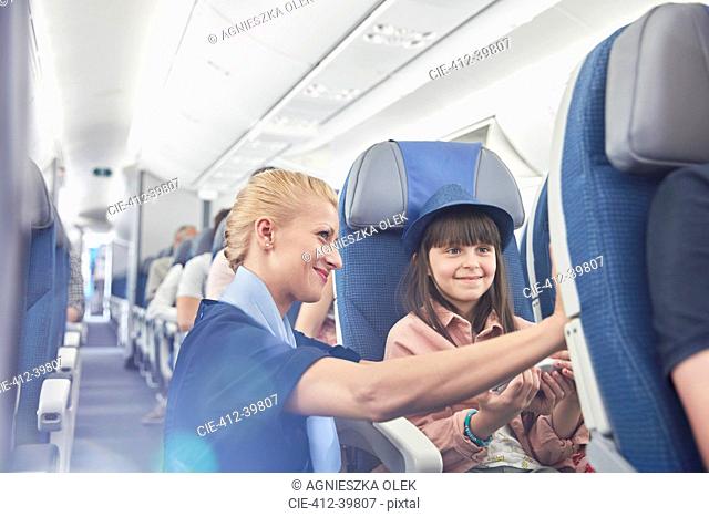 Flight attendant helping girl passenger on airplane