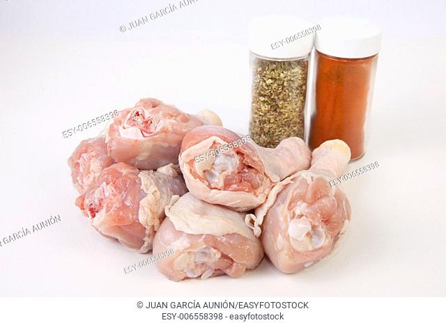 Chicken thighs or legs with spice bottles. Isolated over white background