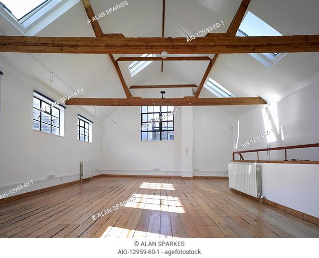 Empty office space with exposed timber beams and velux windows, UK