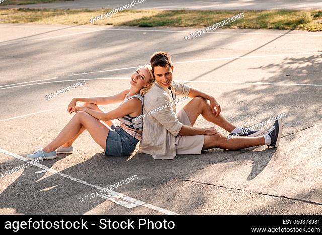 happy couple sitting on basketball playground