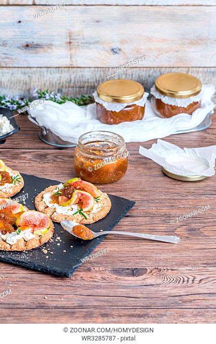 Canape or crostini with multigrain crispread with cream cheese and fig jam on a slate board. Delicious appetizer ideal as an aperitif