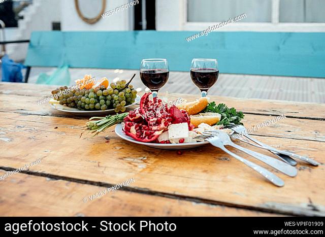 Georgia, Tbilisi, Fresh fruit and glasses of red wine on wooden table outdoors