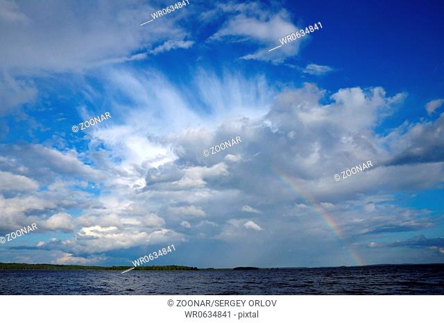 Colorfull rainbow under single cloud over lake