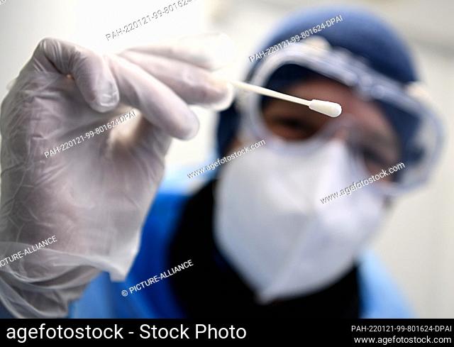 20 January 2022, Berlin: Oliver Müller, a doctor, holds a test stick for taking a sample for a PCR test at the Neukölln health department