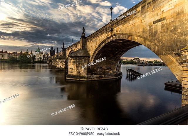 A view through the arch of Charles Bridge at sunrise, in the background Old Town and the National Theater