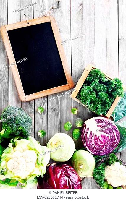 Close up Fresh Assorted Vegetable for Salad with Chalkboard on Wooden Table. Emphasizing Copy Space