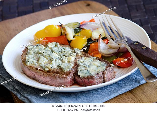 Steak topped with melted blue cheese with roast vegetables