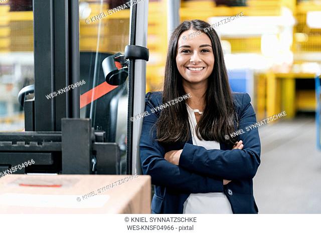 Confident woman standing in logistics center, with arms crossed