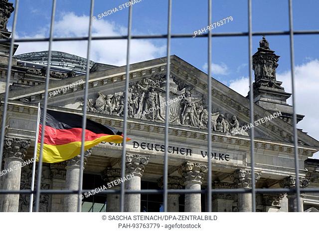The Reichstag building and German flag viewed through a fence, 21.05.2017. The Reichstag building at Platz der Republik in Berlin-Tiergarten has been the seat...