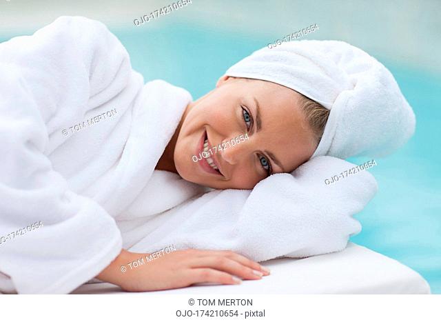 Woman with head wrapped in towel laying poolside