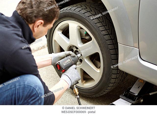 Germany, Bavaria, Kaufbeuren, Mature man changing car tire