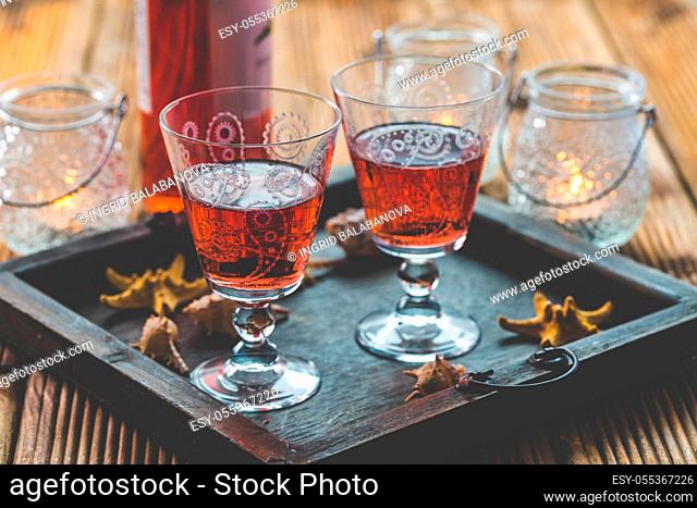 Two vintage glasses of red wine with bottle and lantern on wooden background