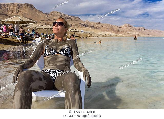 Woman smeared with mineral mud sunbathing, Dead Sea, En Bokek, Israel, Middle East