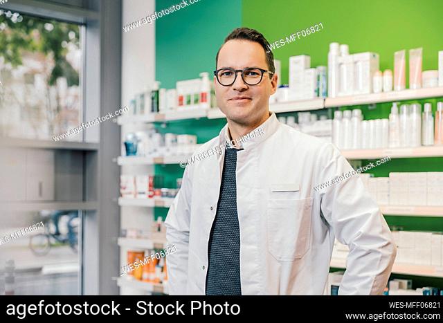 Smiling pharmacist wearing lab coat while standing in chemist shop