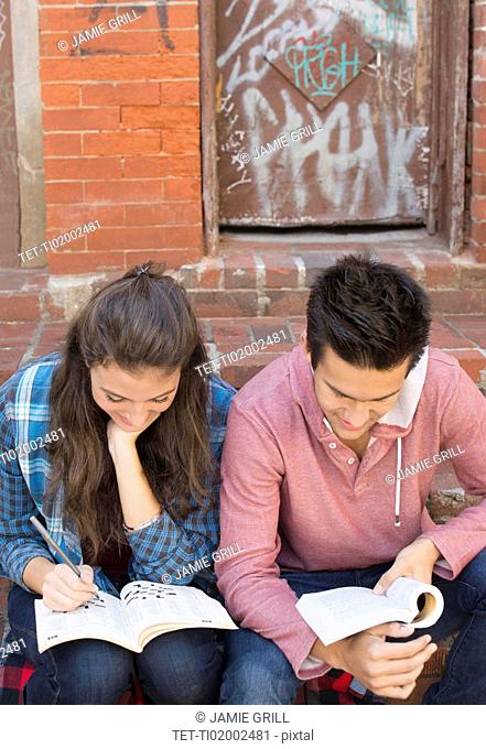 Young couple reading book and doing crossword