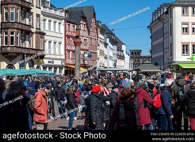 04 April 2023, Rhineland-Palatinate, Trier: Tourist groups stand at the market cross on the main market in the city center