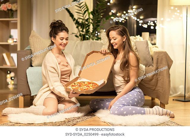 happy female friends with pizza at home