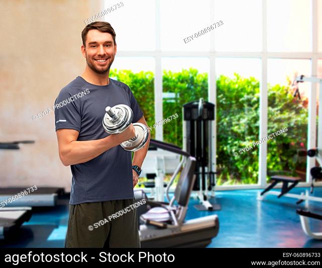 happy smiling man exercising with dumbbells in gym